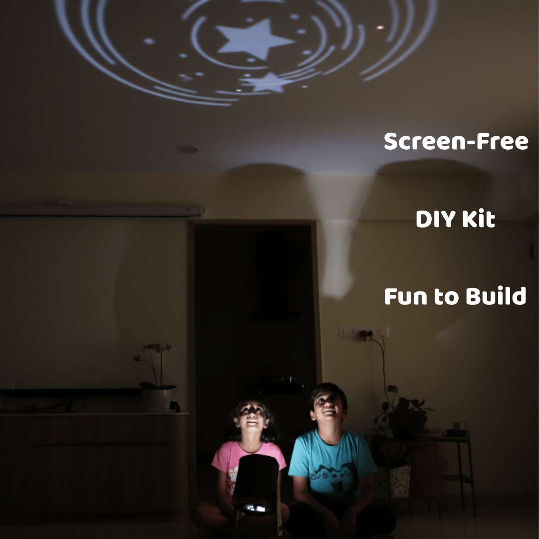 Two children sitting in a dark room watching a star-shaped projection on the wall, with text 'Screen-Free DIY Kit Fun to Build' above them.