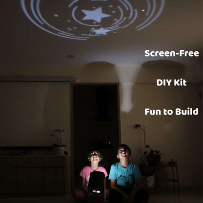 Two children sitting in a dark room watching a star-shaped projection on the wall, with text 'Screen-Free DIY Kit Fun to Build' above them.